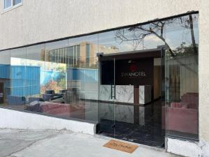 a glass facade of a building with a sign on it at Swanotel Gachibowli in Gachibowli