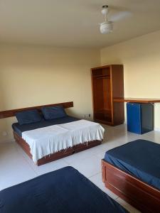 a bedroom with two beds and a cabinet at Maria Flor Pousada e kitnet in São Mateus