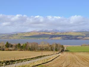 a field with a fence next to a body of water at The Shepherds Hut - Uk46633 in Culbokie