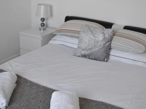 Una cama con sábanas blancas y una almohada. en The Lodge - Uk46636, en Culbokie