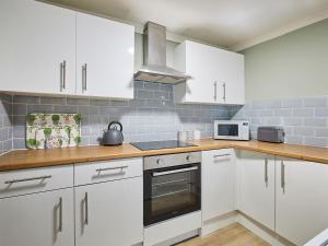 uma cozinha com armários brancos e um forno com placa de fogão em Cobblers Cottage em Barnard Castle