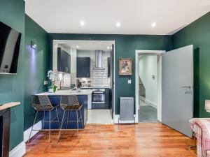 a kitchen with blue and green walls and wooden floors at Ethelbert Apartment in Westgate-on-Sea