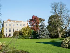 una grande casa bianca con alberi di fronte di The Coach House At Waterperry Gardens a Waterperry