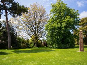 a park with trees and a sign in the grass at The Coach House At Waterperry Gardens in Waterperry