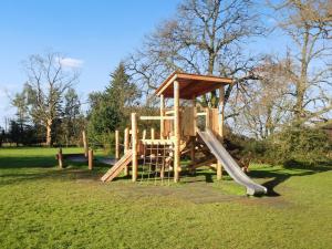 a wooden playground with a slide in a park at The Coach House At Waterperry Gardens in Waterperry