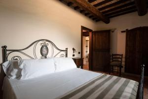 a bedroom with a bed with white sheets and a chair at Birrificio del Catria in Cantiano