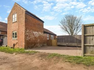 a brick building with a gate and a fence at The Barn in Martham