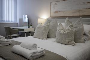 um quarto com uma cama com lençóis brancos e almofadas em The 1878 by STAMP SA em Blackpool