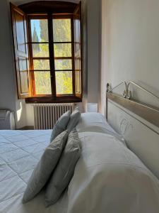 a bed with four pillows on it with a window at Castello Vicchiomaggio in Greve in Chianti