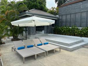 2 sedie a sdraio e un ombrellone su un patio di UMiiMAAN pool villa, 4BR, 4BA a Ko Samui