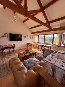 ein Wohnzimmer mit einem Ledersofa und einem Tisch in der Unterkunft Neuadd Villa in Llanwnen