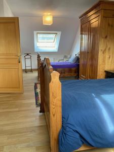 um quarto com uma cama de madeira e um edredão azul em Le Poulailler em Loué