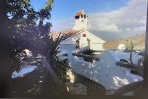 a small white church with a steeple on a building at Guesthouse Un Poco Mas in Canillas de Aceituno