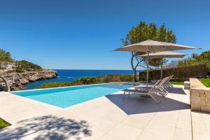 a swimming pool with an umbrella and a chair at Vista DOr in Cala d´Or