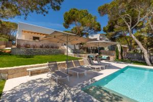 a house with a swimming pool with chairs and an umbrella at Vista DOr in Cala d´Or