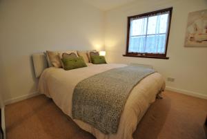 1 dormitorio con 1 cama grande con almohadas verdes en Meadowshores Apartment Crail, en Crail