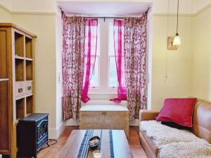 a living room with a window with pink curtains at Tern Cottage in Bognor Regis