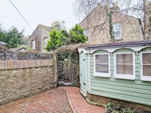 a green house next to a brick fence at Tern Cottage in Bognor Regis