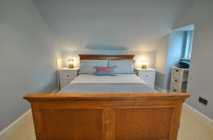 a bedroom with a wooden bed with two lamps on it at The House on the Square- Coastal Townhouse in Saint Monance