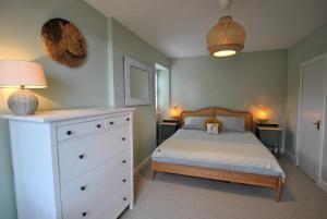 a bedroom with a bed and a dresser with a dog on it at The House on the Square- Coastal Townhouse in Saint Monance