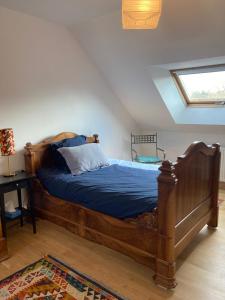 um quarto com uma grande cama de madeira com lençóis azuis em Le Poulailler em Loué