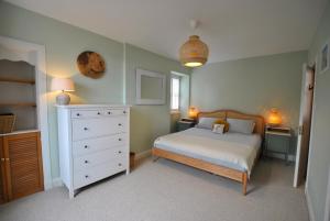 a bedroom with a white bed and a dresser at The House on the Square- Coastal Townhouse in Saint Monance