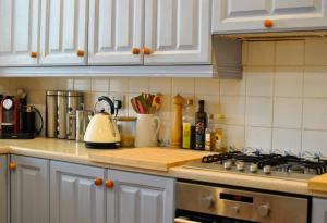 a kitchen with white cabinets and a stove top oven at The House on the Square- Coastal Townhouse in Saint Monance