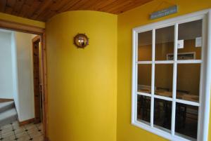 a yellow room with a window and a clock on the wall at The House on the Square- Coastal Townhouse in Saint Monance