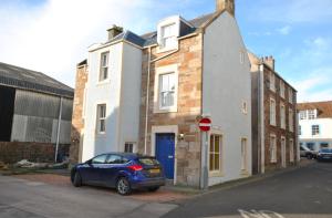 a small blue car parked in front of a building at The House on the Square- Coastal Townhouse in Saint Monance