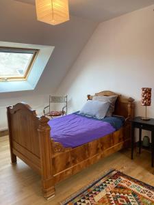 um quarto com uma cama de madeira num sótão em Le Poulailler em Loué