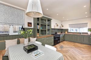 uma cozinha com armários verdes e uma mesa numa cozinha em Luxury Christchurch Retreat em Iford
