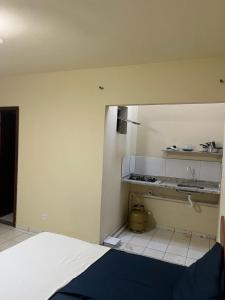 a room with a kitchen with a counter and a room with at Maria Flor Pousada e kitnet in São Mateus