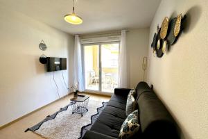 a living room with a black couch and a television at Les Naïades E20 - 2 bedrooms for 5 people ! in Avène
