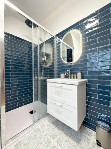 ein Badezimmer mit einem Waschbecken und einer Dusche mit blauen Fliesen in der Unterkunft La Meslaysienne - Comfortable house, swimming pool in Meslay-le-Vidame