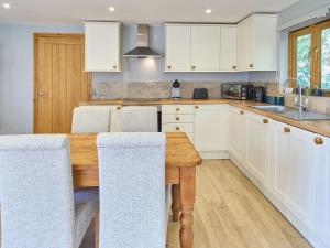 a kitchen with a wooden table and white cabinets at Host & Stay - Orchard Barn in Ashford