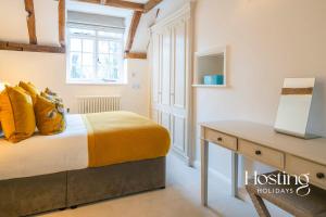 een slaapkamer met een bed met gele kussens en een bureau bij Stable Annex Bisham - Vibrant 1 Bed With Parking in Marlow