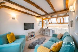 a living room with a blue couch and a tv at Stable Annex Bisham - Vibrant 1 Bed With Parking in Marlow