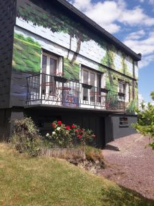 een groen en wit gebouw met 2 balkons en bloemen bij Maison de 4 chambres avec jardin clos et wifi a Villers sous Foucarmont in Villers-sous-Foucarmont