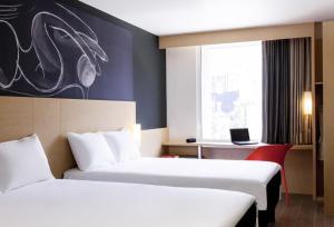 a hotel room with two beds and a window at Ibis Mexico Alameda in Mexico City
