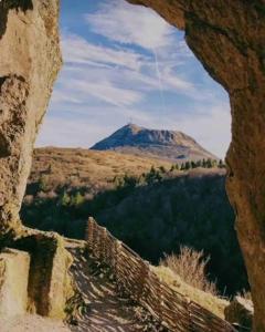 uma vista para uma montanha através de um buraco numa parede em Un havre de paix à la campagne près Vulcania em La Goutelle