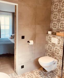 a bathroom with a toilet and a bed at De Molenhoeve in Voeren