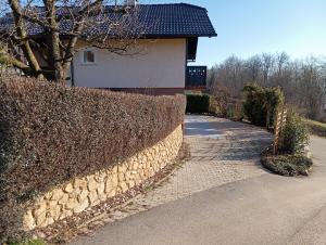 a stone wall next to a house and a driveway at Vineyard cottage Tilka in Novo Mesto