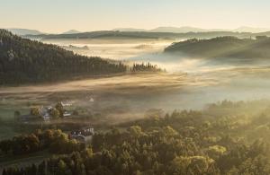 un valle nebuloso en las montañas con una casa y árboles en Hotel Adršpach en Adršpach