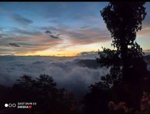 a view of a foggy valley with a sunset at Diksha Homestay in Darjeeling