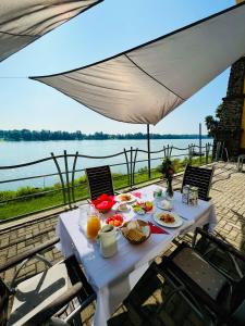 einen Tisch mit Nahrung und Blick auf das Wasser in der Unterkunft SZIGET HOTEL VERÁNKA in Érsekcsanád