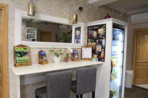 eine Bar in einer Küche mit 2 Stühlen und einem Kühlschrank in der Unterkunft Zenit Panzió in Miskolctapolca