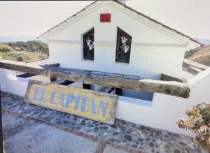 a small white house with a sign in the window at Guesthouse Un Poco Mas in Canillas de Aceituno