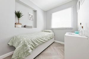 biała sypialnia z łóżkiem i oknem w obiekcie Spacious 3 Bedroom Modern House with Garden w mieście Kent