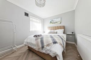 een witte slaapkamer met een bed en een raam bij Spacious 3 Bedroom Modern House with Garden in Kent