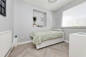 a white bedroom with a bed and a window at Spacious 3 Bedroom Modern House with Garden in Kent